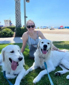 Woman sitting on grass with two dogs on a beach | 24th Street Dental Biltmore in Phoenix, AZ